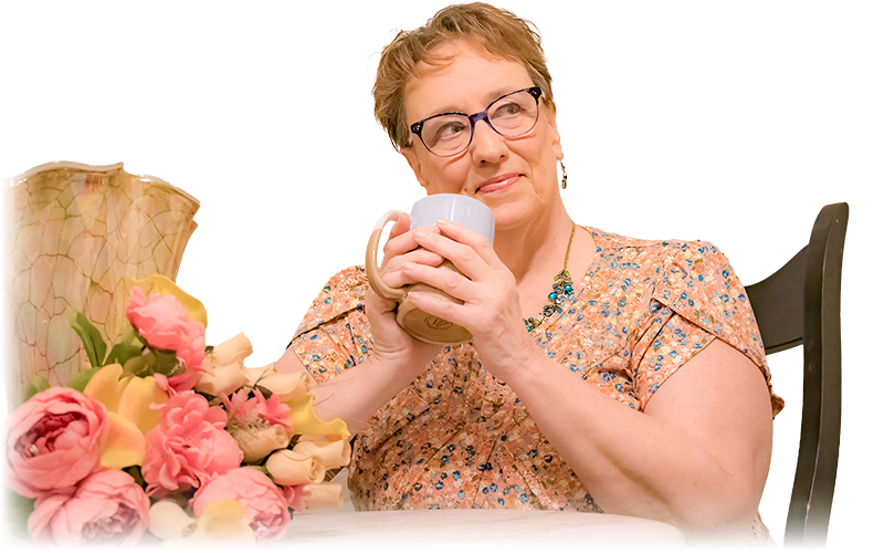 Photo of Delisa at a table sipping on coffee looking contemplative.