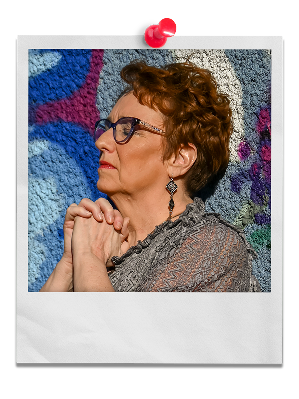 Photo of Coach Delisa praying next to a colorful painted wall.